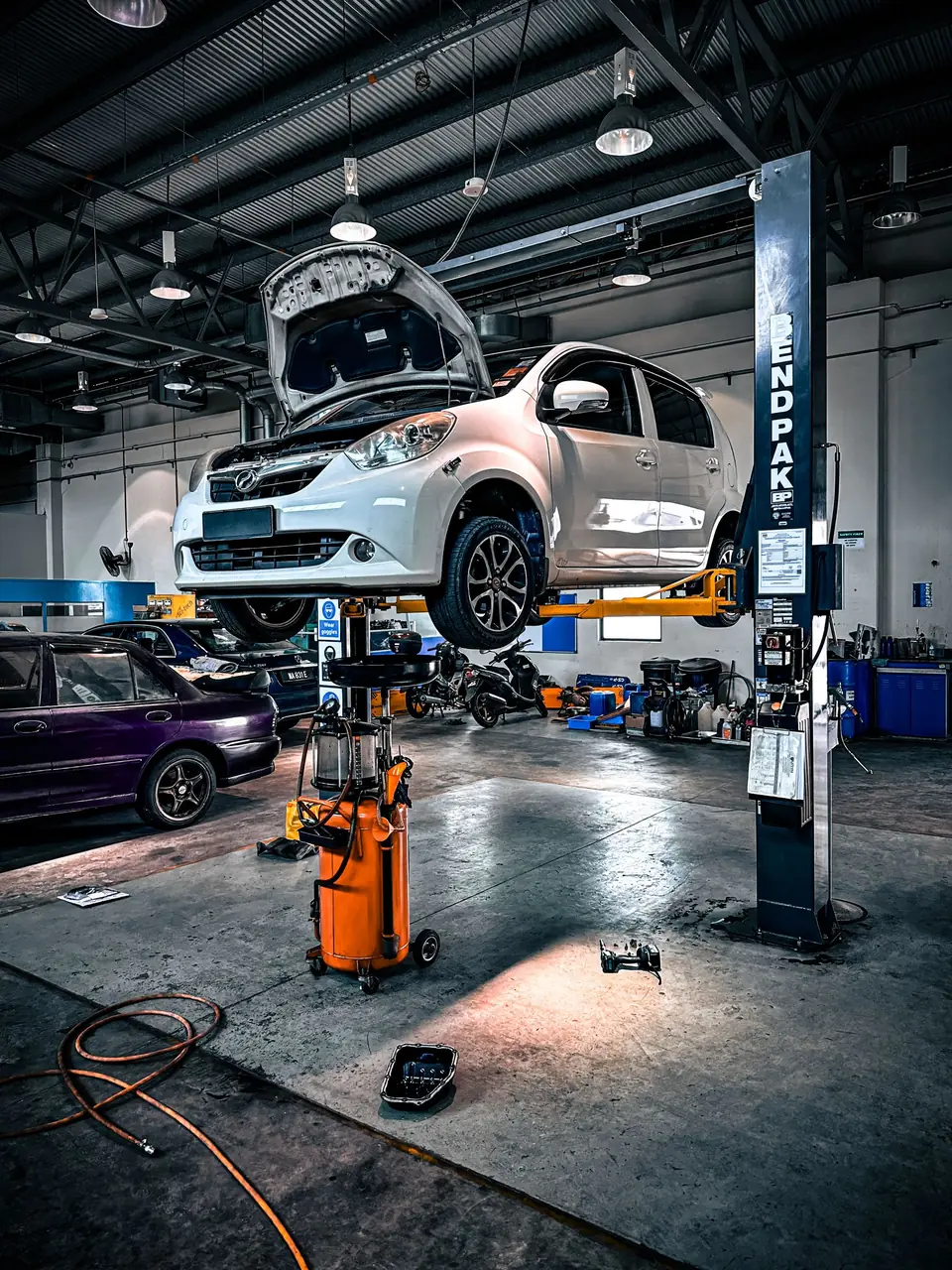 A vehicle raised on a lift in a busy workshop